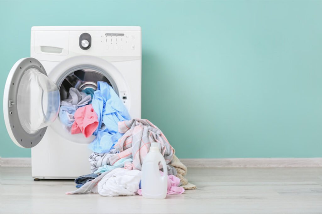 Roupas para fora de uma máquina de lavar.