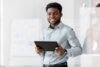 Homem executivo sorrindo com um tablet na mão.