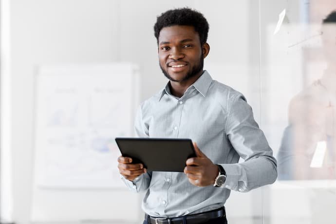 Homem executivo sorrindo com um tablet na mão.