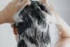 Uma mulher passando shampoo no cabelo