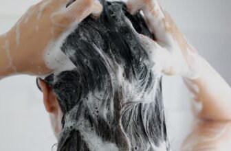 Uma mulher passando shampoo no cabelo