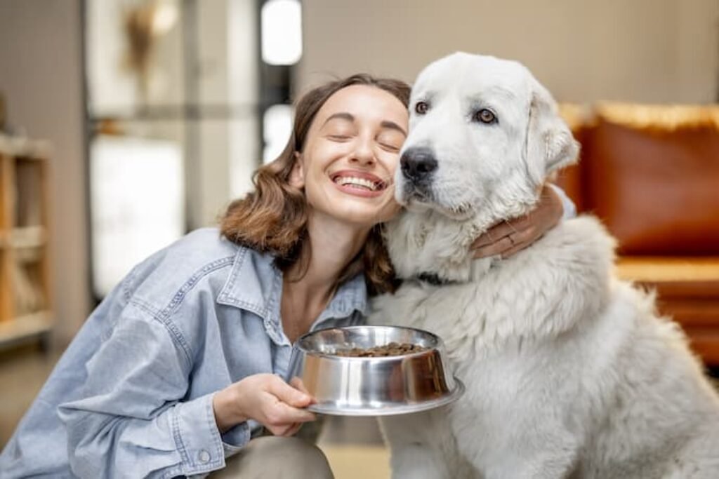 Uma tutora com rosto colado em um cão grande