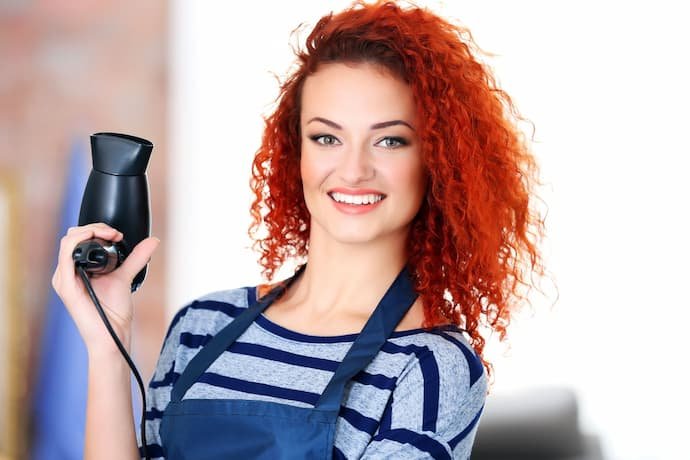 Mulher com cabelo cacheado ruivo.