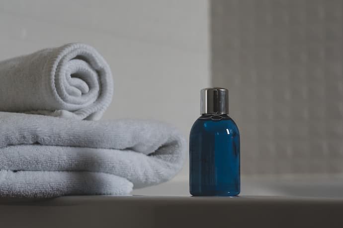 Frasco de shampoo ao lado de toalhas.