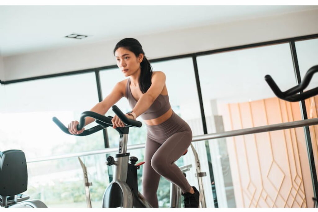 Mulher na academia pedalando em uma bicicleta ergométrica.
