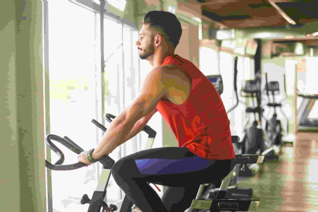 Rapaz fazendo seu treino com uma bicicleta ergométrica.