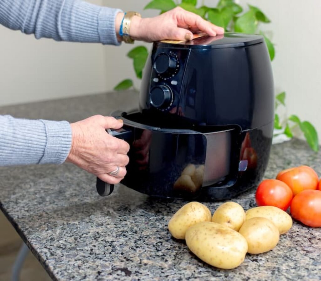 Uma mulher abrindo um airfryer pequeno.