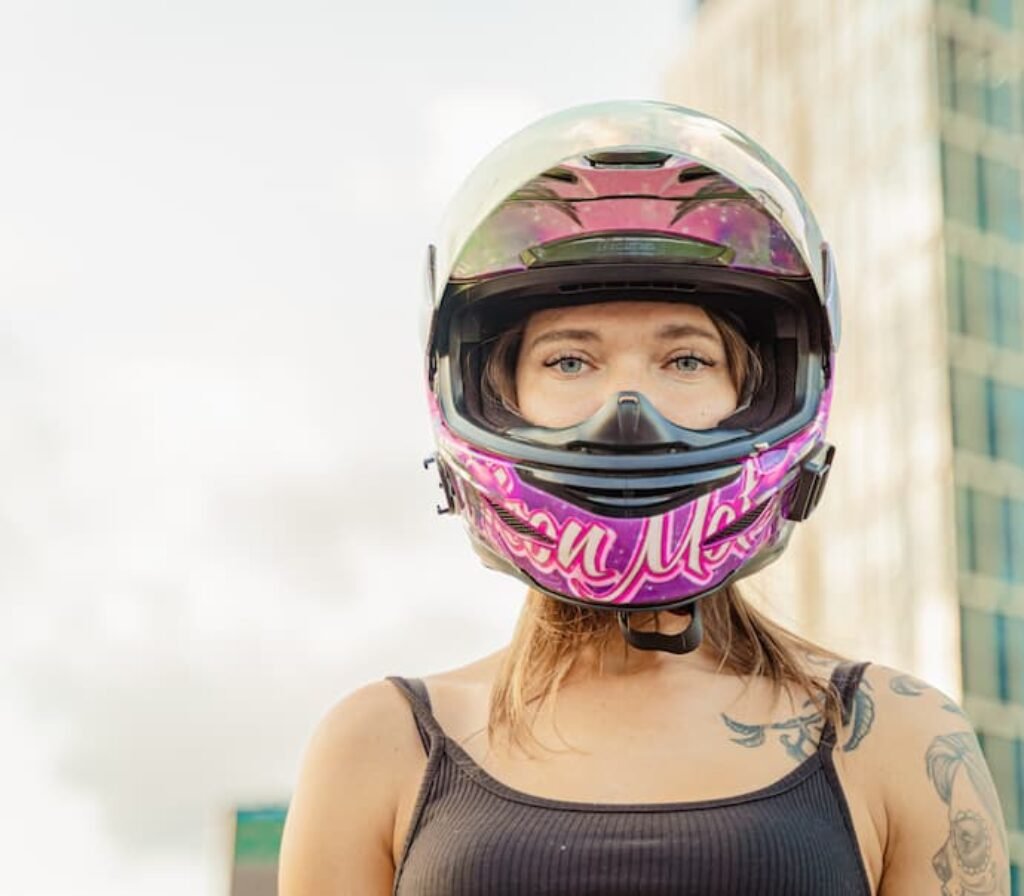 Uma mulher usando um capacete de moto sem viseira.