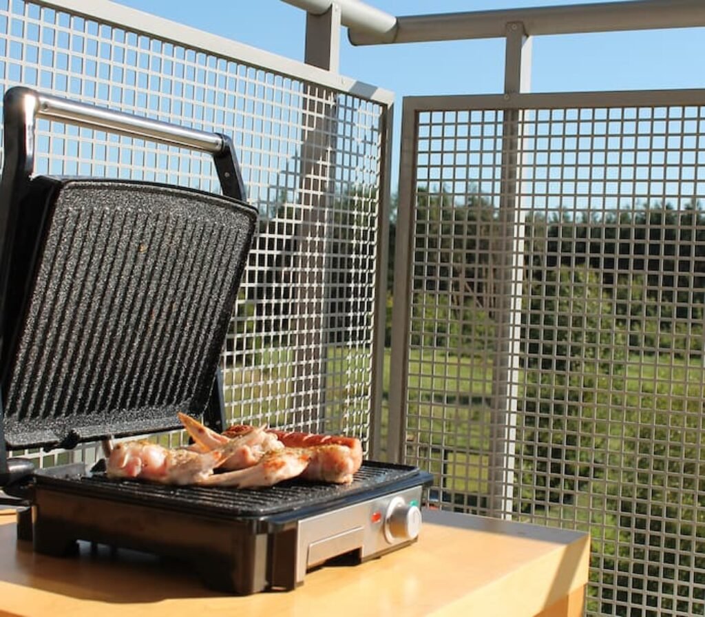 Um grill para carnes assando frango em uma área externa.