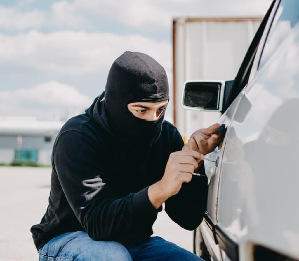 Um ladrão tentando abrir a porta de um carro.