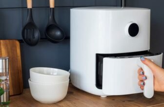 O melhor air fryer na cor branca em cima de uma mesa ao lado de duas tigelas.