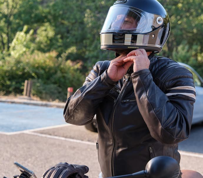 Um homem com jaqueta de couro tirando o melhor capacete de moto da cabeça.