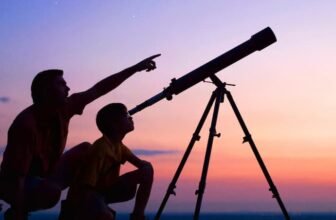 Uma pessoa olhando no telescópio e outra pessoa apontando o dedo para o céu