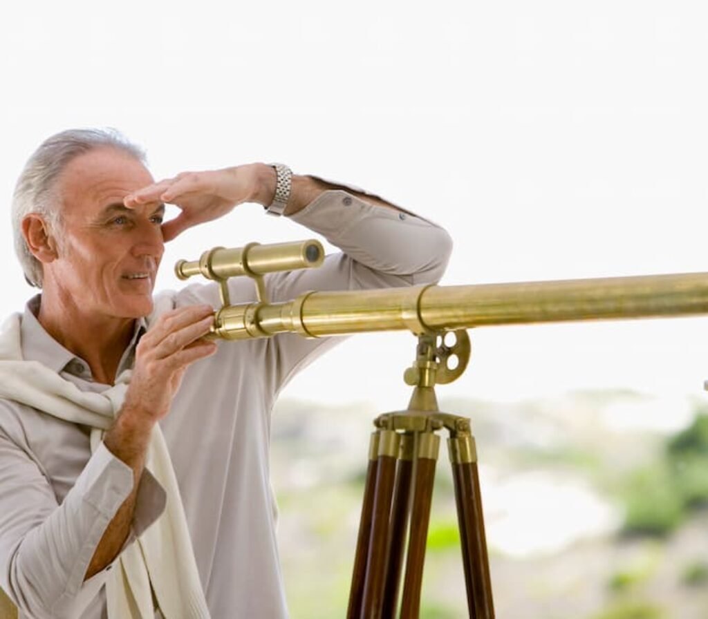 Um homem idoso usando um telescópio dourado.