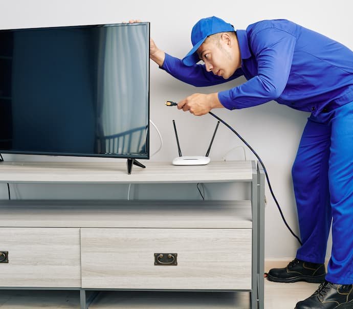 Uma homem instalando uma melhor antena digital interna em um televisor.