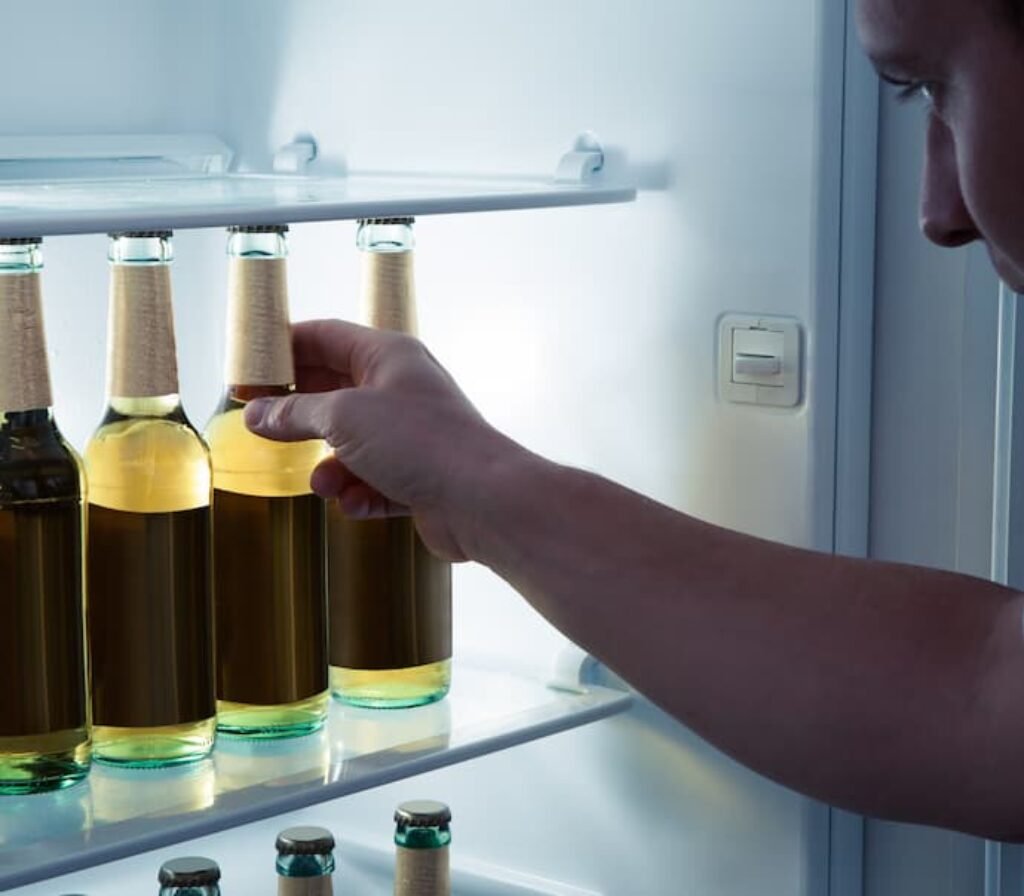 Um homem pegando uma garrafa de cerveja em uma melhor cervejeira residencial.