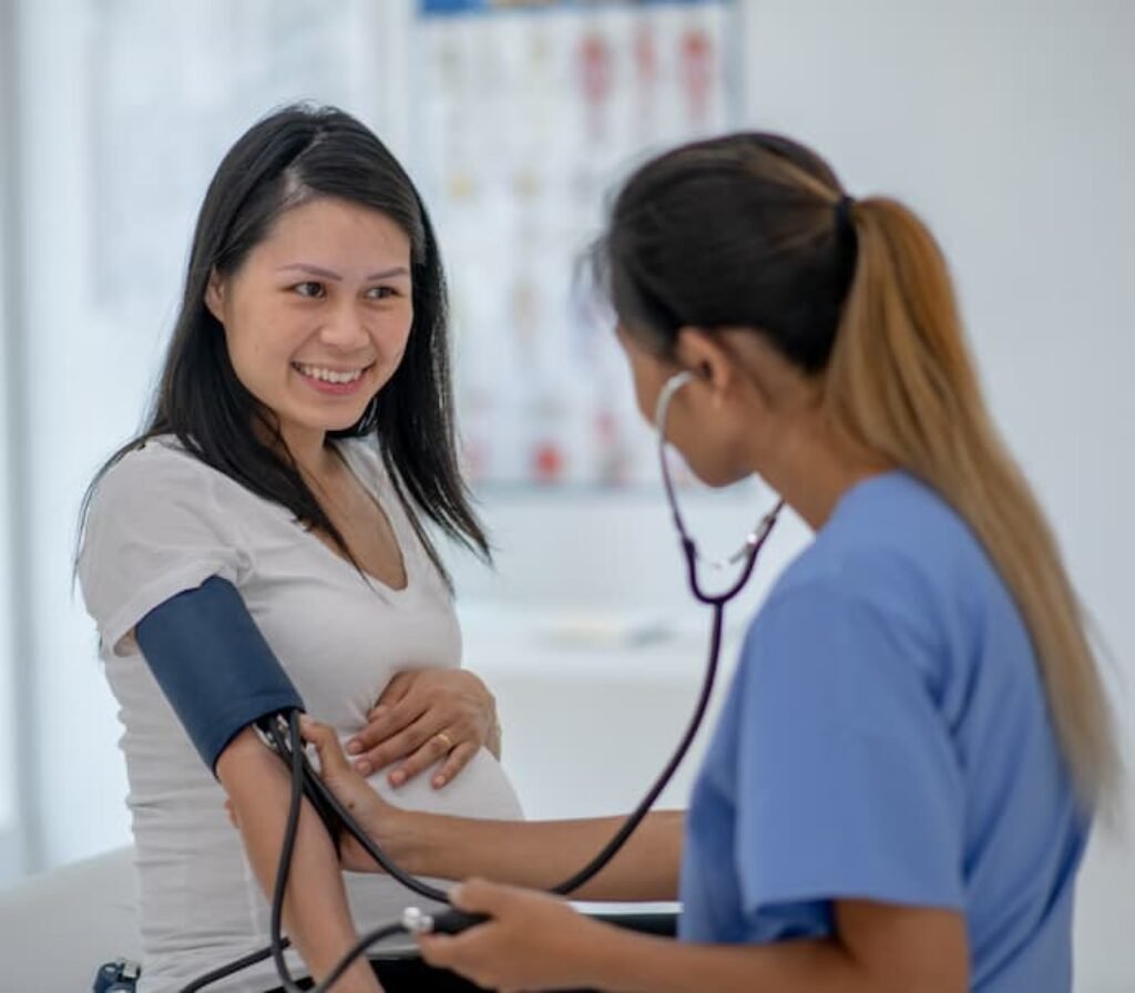 Uma pessoa sorrindo enquanto está tendo a pressão medida por uma enfermeira.