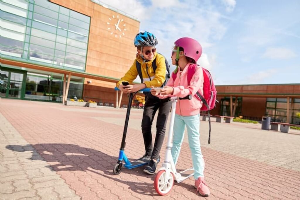 Duas crianças de patinete.