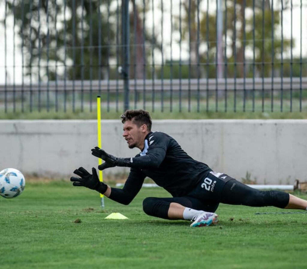 Um goleiro profissional treinando em um campo de fubebol