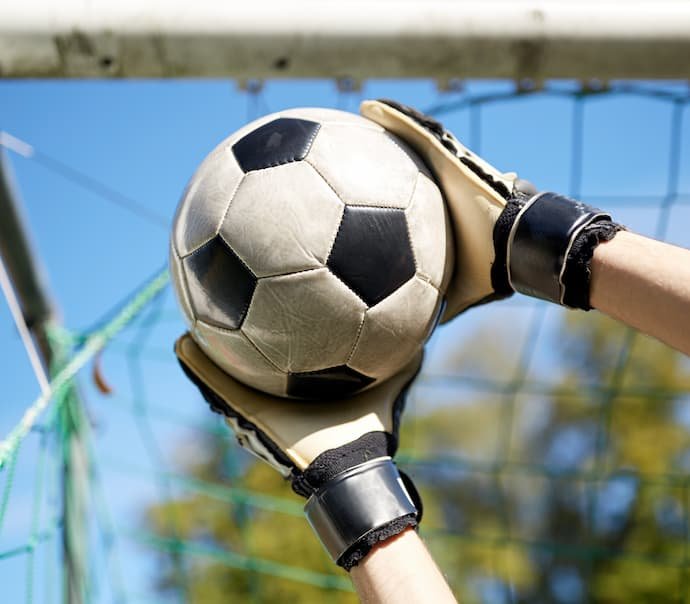 Um goleiro defendendo uma bola com a melhor luva de goleiro.