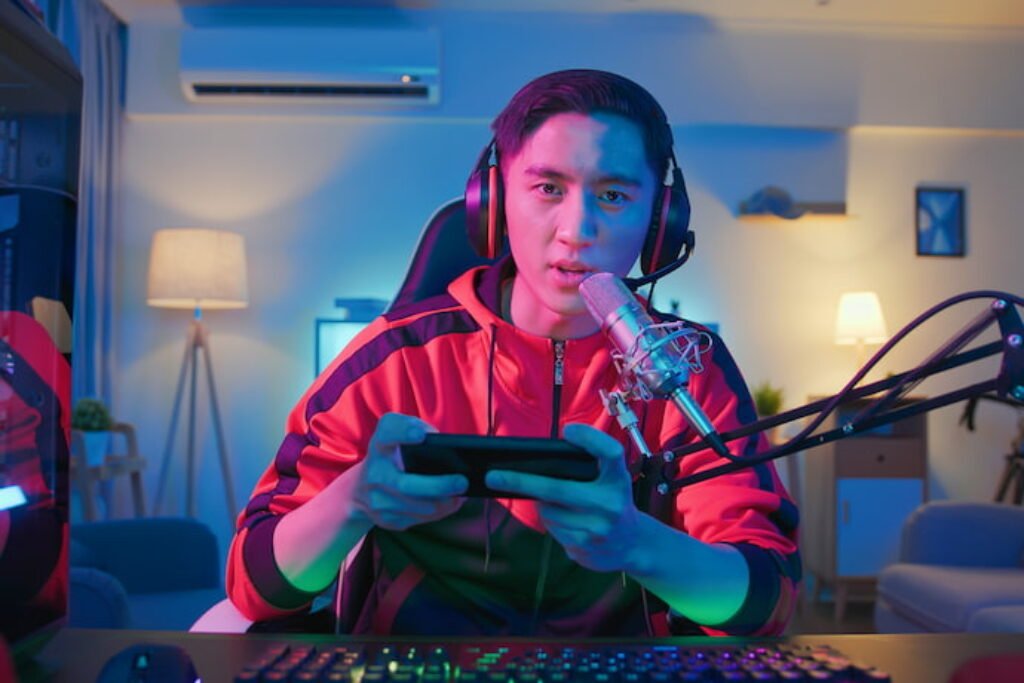 Menino jogando no celular e falando em um microfone.