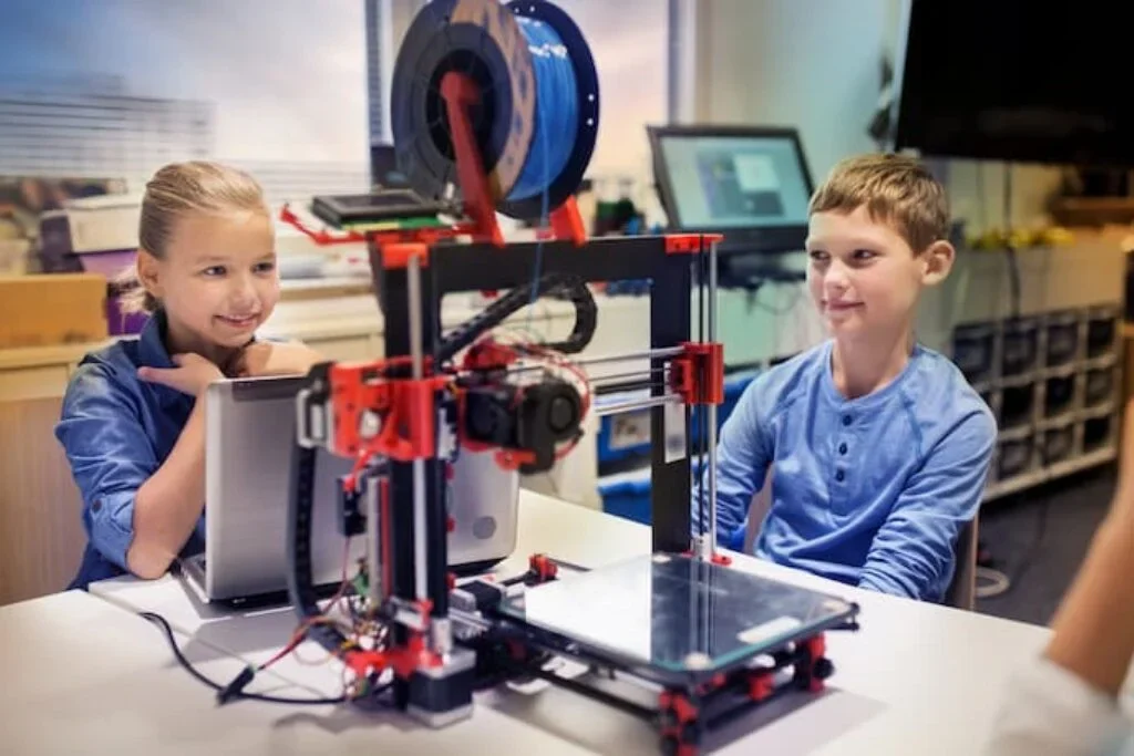 Crianças usam uma impressora 3D para iniciantes.