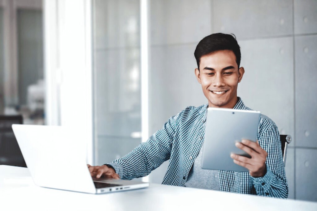 Um homem que segura o melhor tablet custo-benefício com uma mão e com a outra mão mexe no note.