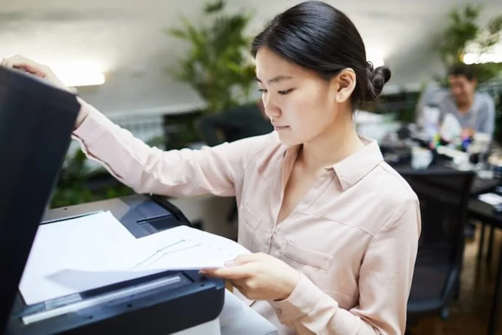 Uma mulher digitalizando um documento em uma impressora.