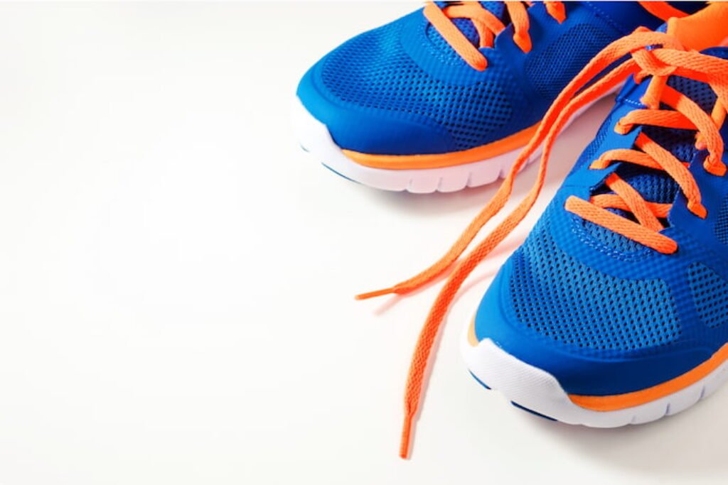 Tênis azul com cadarço laranja em um fundo branco.