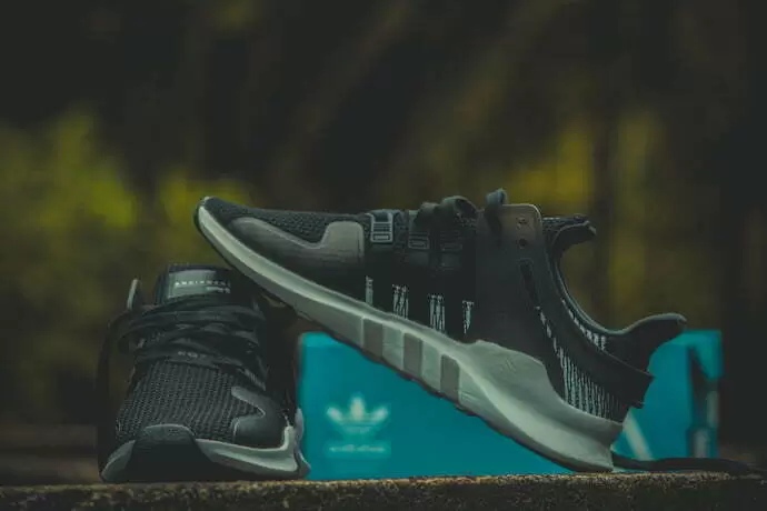 Tênis Adidas com uma caixa ciano atrás.