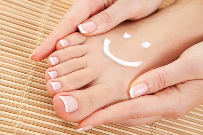 Um creme desenhado como um sorriso no pé de uma pessoa.