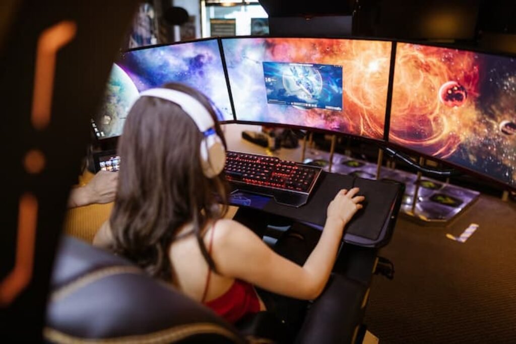 Uma garota em frente a 3 dos melhores monitores 4k.