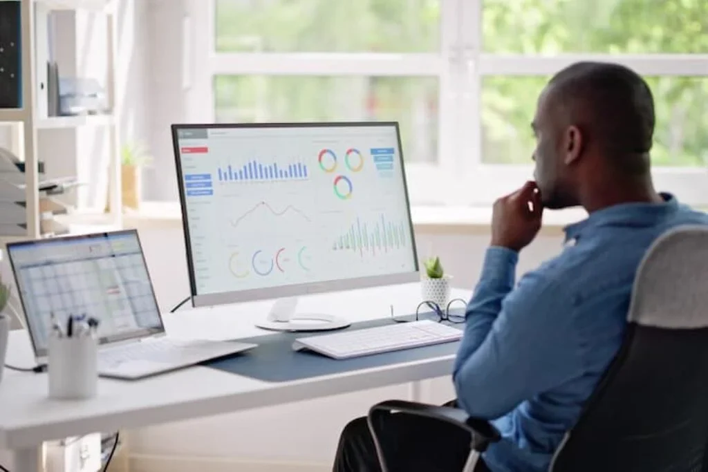 Um homem analisando gráficos em um monitor 4k.
