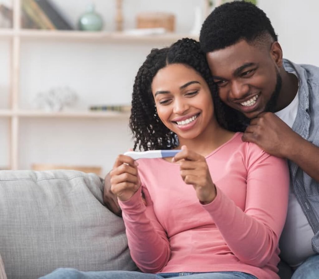 Um casal sorrindo olhando para o resultado de um teste de gravidez.