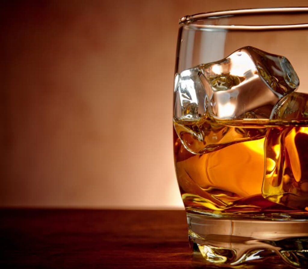 Um copo de whisky em cima da mesa.