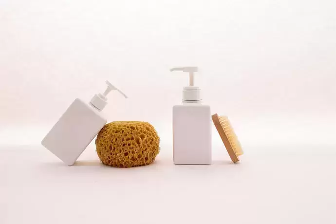 Dois frascos de shampoo ao lado de uma esponja e de um pente.