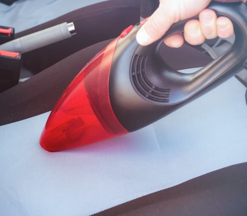 Uma pessoa utiliza um melhor aspirador de pó para carros no estofado.