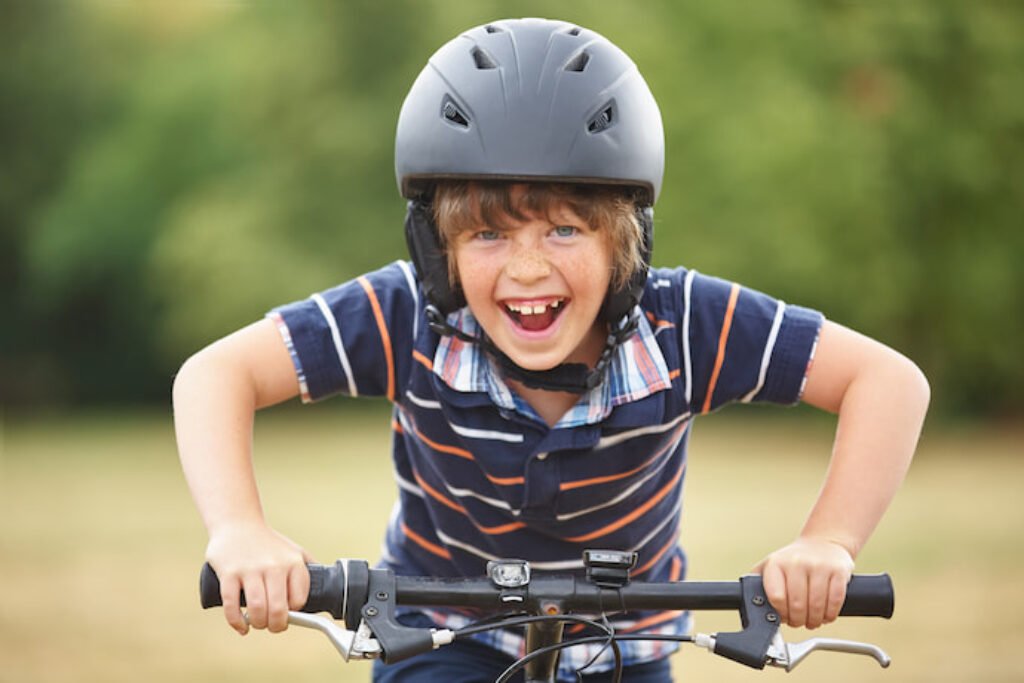 Menino de aproximadamente oito anos andando de bicicleta empolgado.