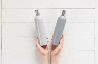 Pessoa segurando frascos de shampoo e condicionador.