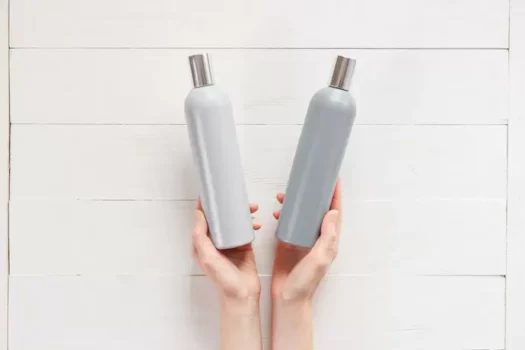 Pessoa segurando frascos de shampoo e condicionador.