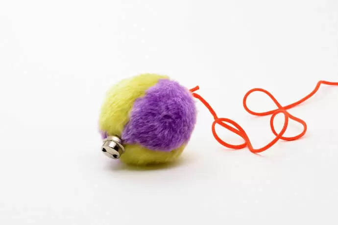 Brinquedo para gato em formato de bola, amarelo e azul, em destaque.