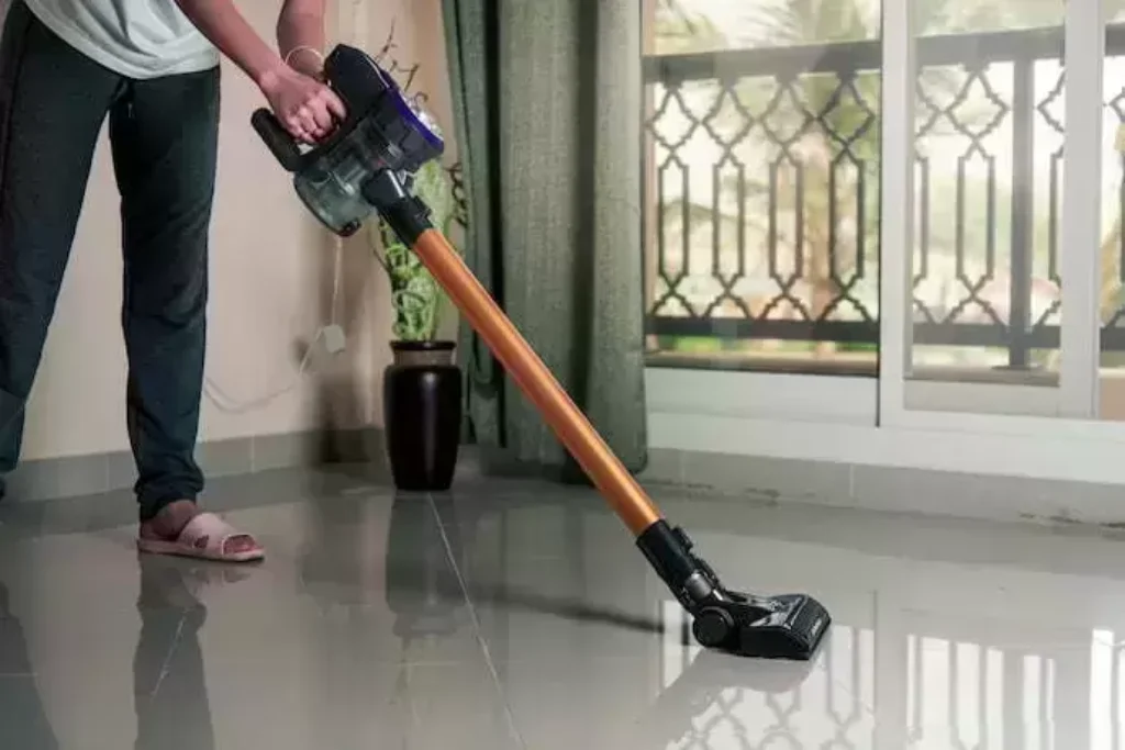 Em uma sala, uma pessoa utiliza um melhor aspirador de pó vertical.
