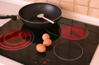 Em cima de um cooktop elétrico hé 3 ovos e uma frigideira.