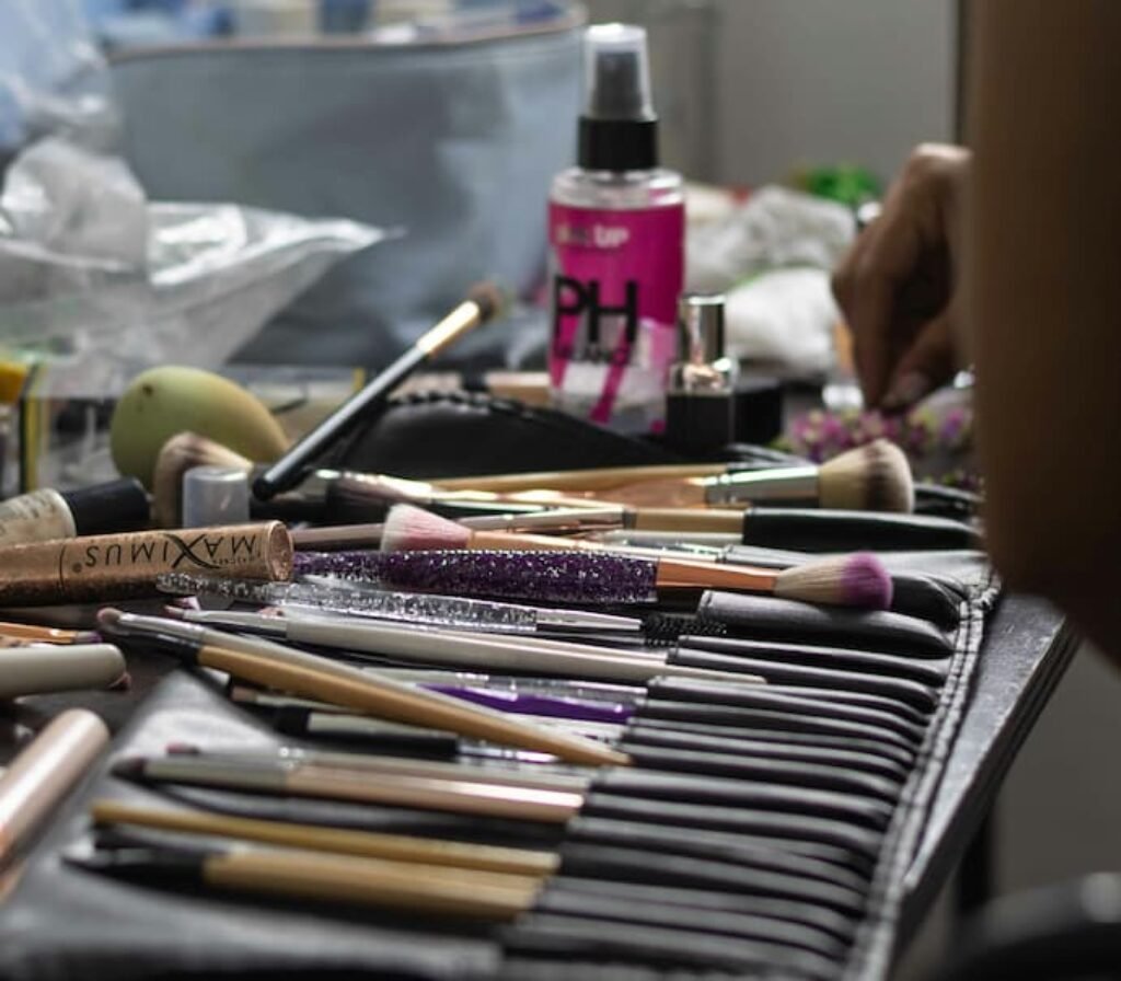 O melhor kit de pincéis de maquiagem em um estojo aberto, junto com alguns cosméticos em uma mesa de trabalho de maquiador.