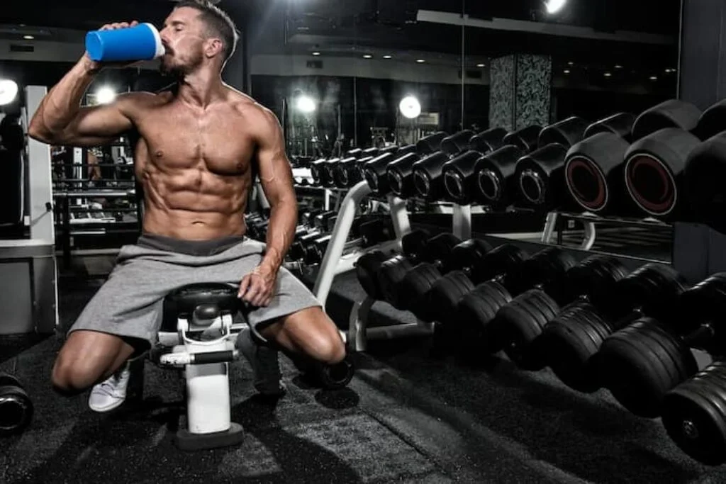 Um homem tomando hipercalórico em uma academia.