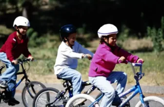 Três crianças andando de bicicleta.