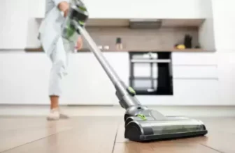 Close no bico de um melhor aspirador de pó que está sendo utilizado para aspirar um piso de uma cozinha.