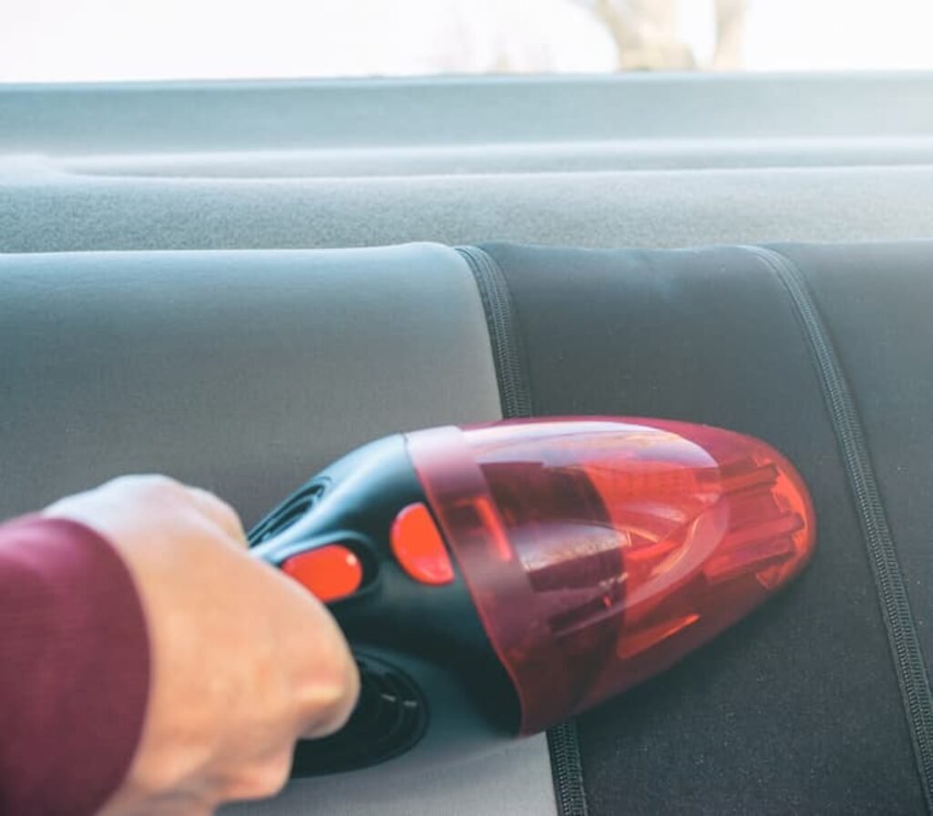 Um aspirador sendo utilizado para aspirar e secar o banco de um carro.