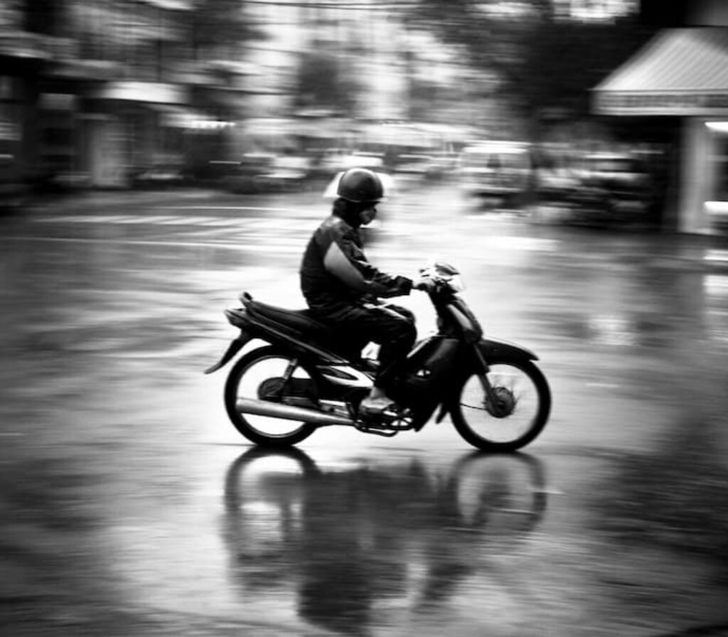 Um motociclista na rua em cima de uma moto e com a melhor capa de chuva para motoqueiro de 2025.