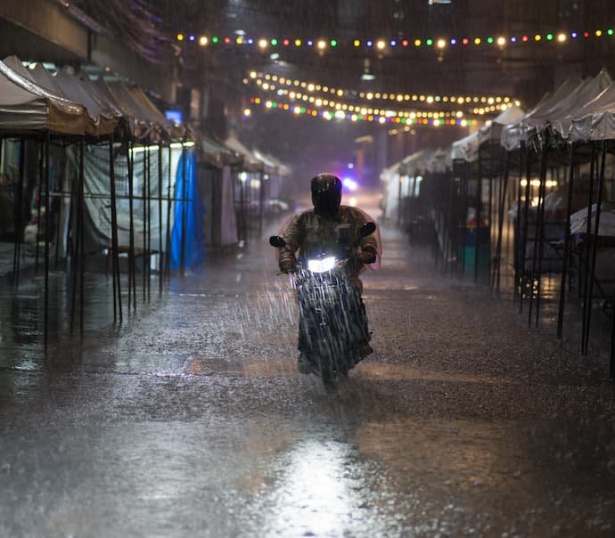 Um motocilista na chuva com a melhor capa de chuva para motoqueiro.